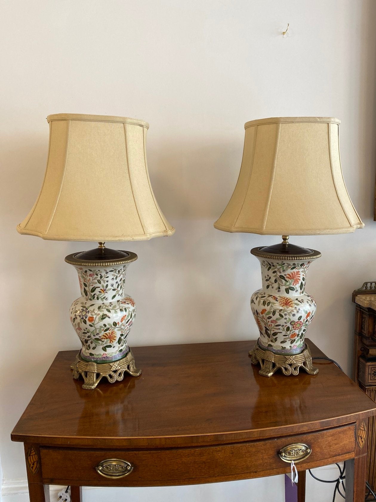 A BEAUTIFUL PAIR OF ASIAN TABLE LAMPS. THE CREAM GROUND CRACKLE GLAZED BALUSTER LAMPS DECORATED WITH FLOWERS ON GILT METAL MOUNTED BASE AND GADROONED BASES WITH SHADES.