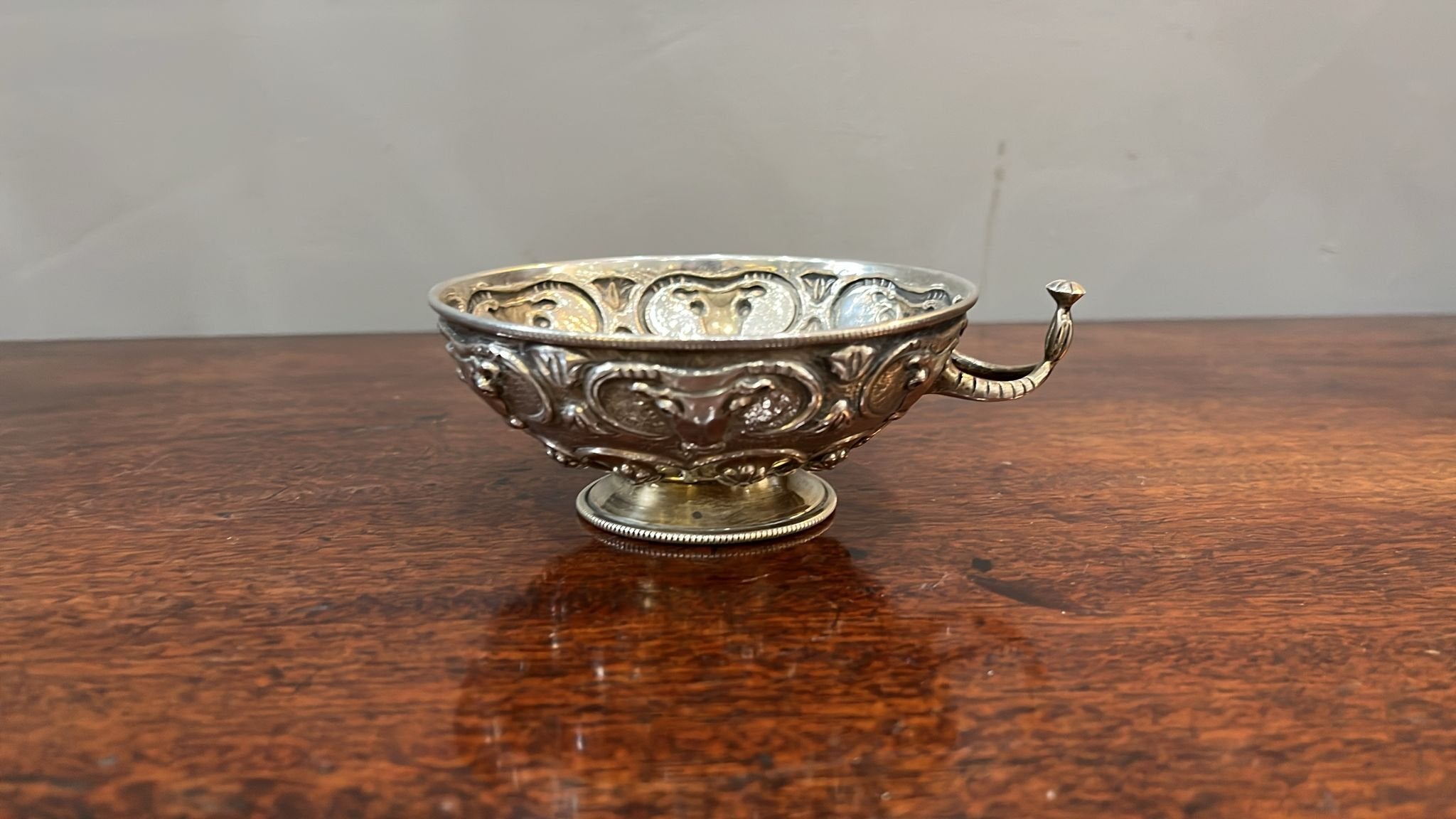 20th century silver tastevin / drinking bowl possibly Greek embossed with bull masks over flowerheads, the single wishbone handle stamped mark 925 raised on circular foot (BN151)